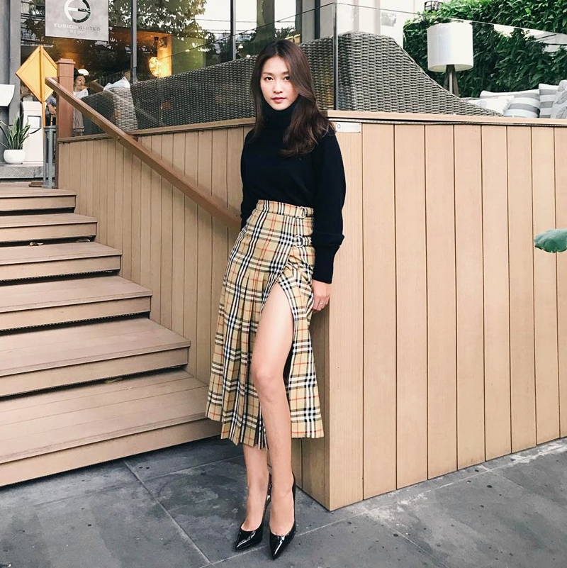 Khả Ngân khoe khéo đôi chân thon dài với chân váy xẻ hông, có họa tiết kẻ nova đặc trưng từ thương hiệu Burberry danh tiếng. Bác sĩ Hoài Phương của “Hậu duệ mặt trời” phiên bản Việt ưu ái mẫu chân váy hàng hiệu với áo len cổ lọ tuyền đen, tạo nên sự tương phản màu sắc ấn tượng.    