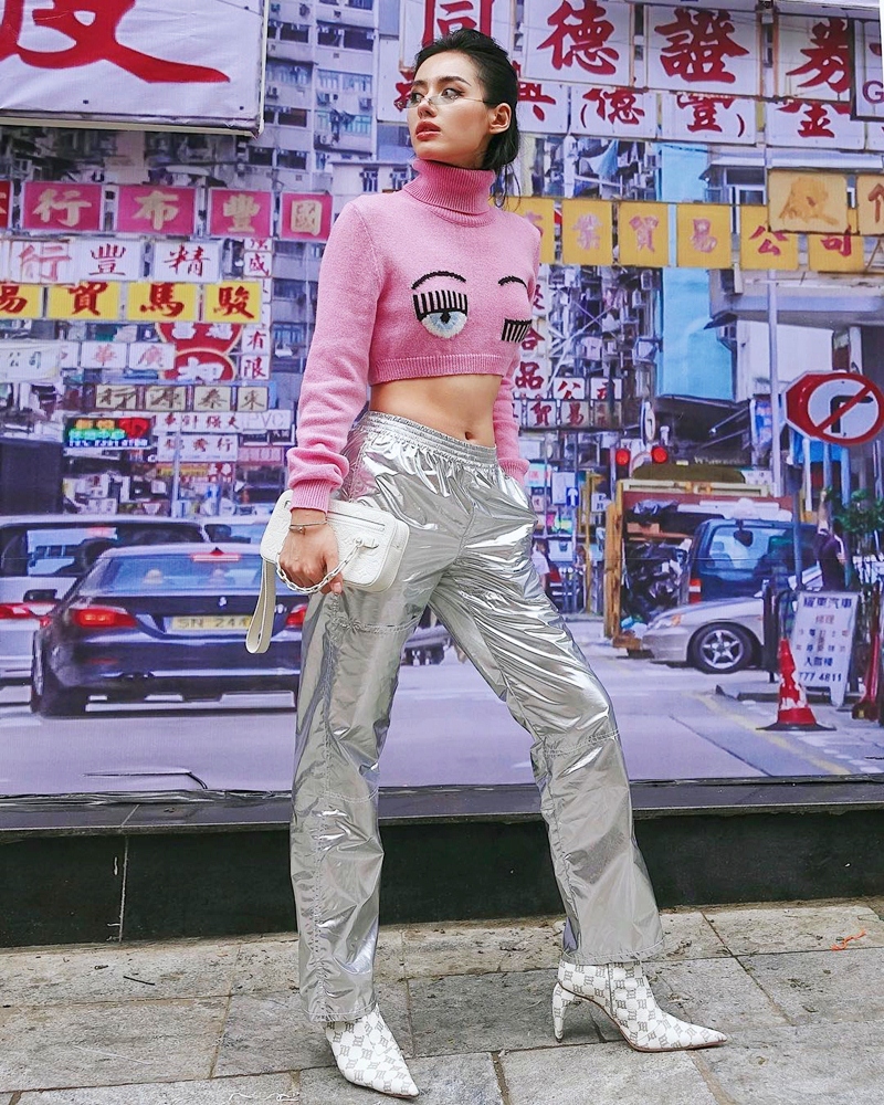 Khánh Linh khoe vòng eo săn chắc với chiếc crop top len hồng, cổ trụ của Chiara Ferragni. Cô nàng còn trổ tài mix đồ sành điệu khi phối item này với quần ánh bạc MM6 Maison Margiela, nhấn nhá bằng đôi boots đặc sắc.    