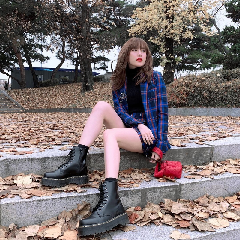 Chọn blazer kẻ tartan, Thiều Bảo Trâm khéo léo ưu ái chân váy ton-sur-ton, mix cùng áo cổ lọ ở trong để giữ ấm trong chuyến đi Hàn Quốc. Cô nàng hoàn thiện phép cộng lý tưởng bằng đôi boots quân đội hầm hố, không quên xách theo chiếc túi đỏ nhỏ xinh để điểm xuyết nét nữ tính.    