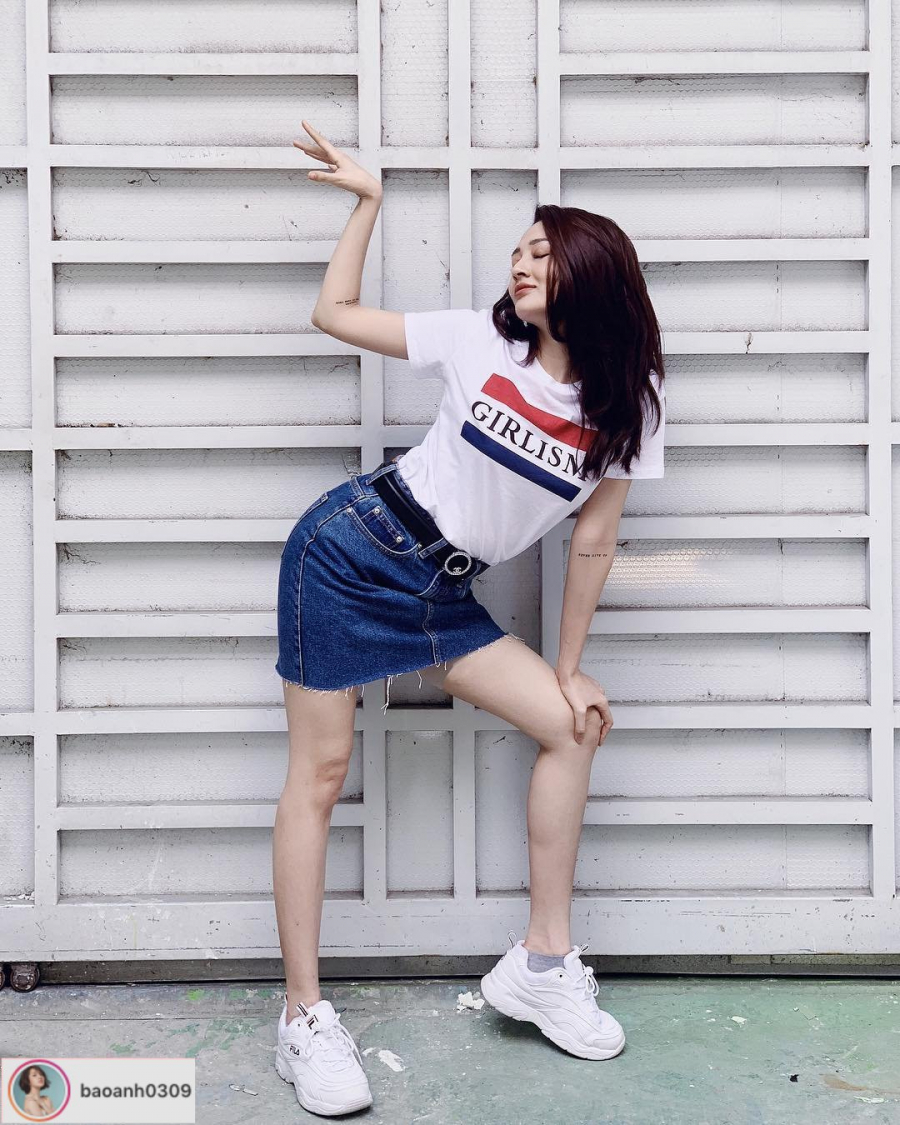 Bảo Anh tinh nghịch với công thức phối đồ kinh điển: áo phông cùng chân váy jeans kèm thắt lưng và giày thể thao trắng.    