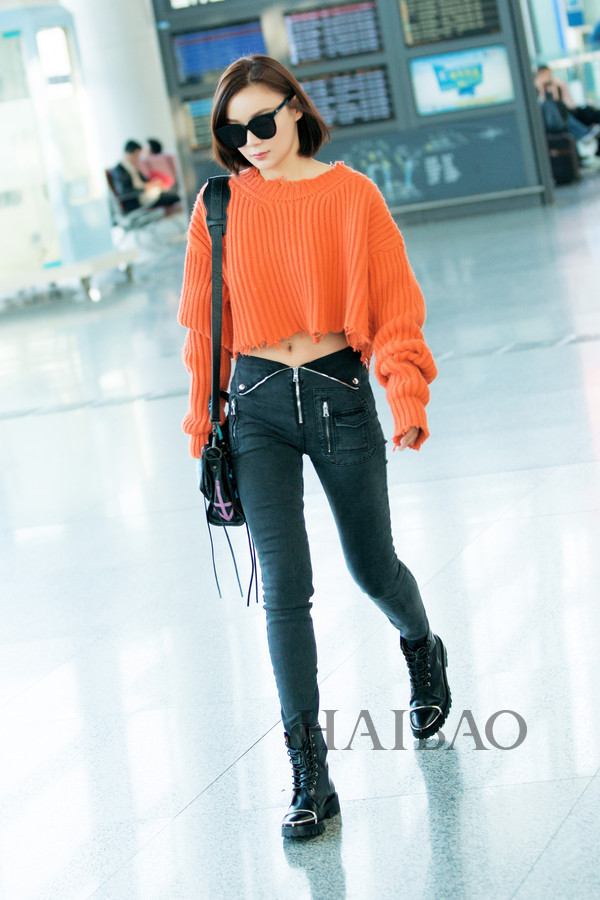 Viên San San sành điệu với áo len crop top cam nổi bật phối cùng quần jeans đen thiết kế khóa kéo ấn tượng.