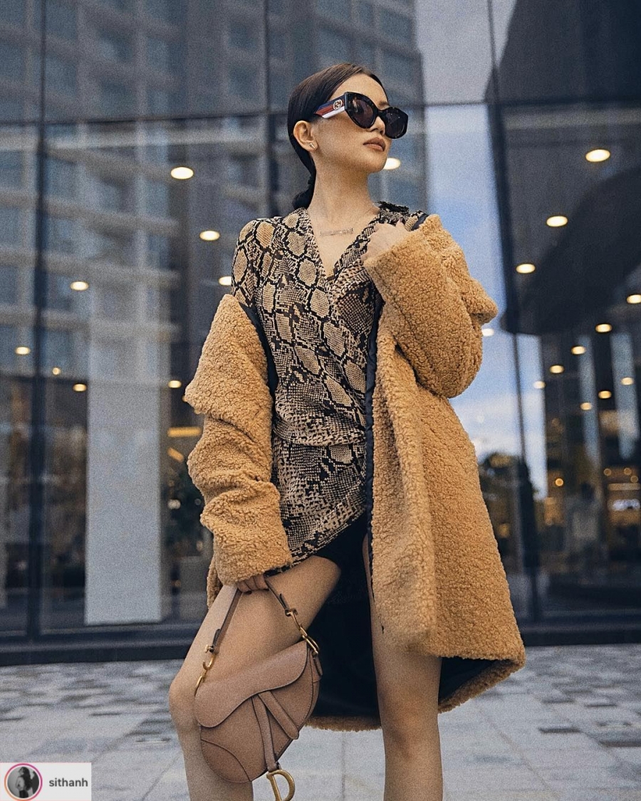Sĩ Thanh bắt kịp xu hướng với váy quấn hoạ tiết da trăn. Bên ngoài là áo khoác lông cừu màu camel. Phụ kiện kính mắt bản to và túi yên ngựa Dior hoàn thiện bộ Shbet999 com đăng nhập.    