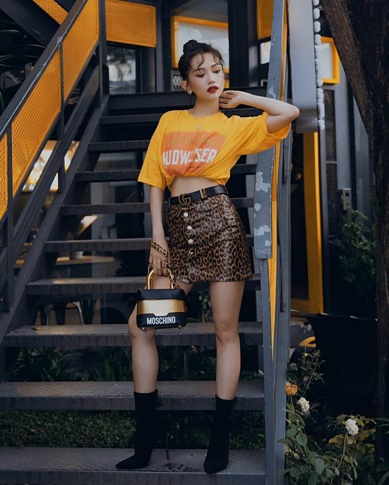 Dù trời trở lạnh hay mưa bão, Sĩ Thanh vẫn tự tin diện áo thun tay ngắn, buột vạt thành crop top khoe eo thon. Chân váy da báo được cô nàng nhấn nhá bằng thắt lưng Gucci. Vẻ sành điệu cũng tăng vọt nhờ đôi boots cổ tất và chiếc túi Moschino [tv] H&M ánh kim xinh xắn.    