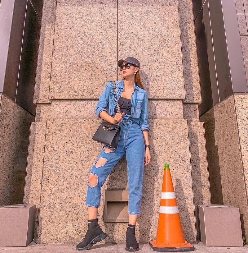 Denim-on-denim là công thức mix đồ giúp Minh Hằng tô đậm phong cách bụi phủi. Nữ ca sĩ khéo chọn giày thể thao , tăng cá tính mạnh mẽ bằng mũ lưỡi trai và kính mắt bản lớn.    