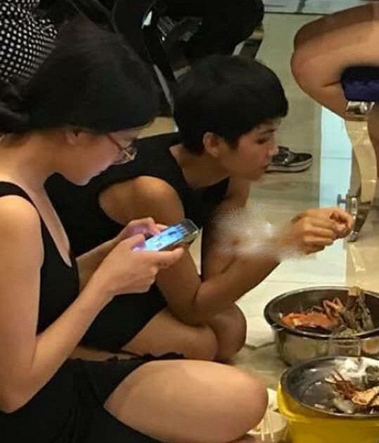 Phương Khánh đeo kính và chăm chú lướt điện thoại.    