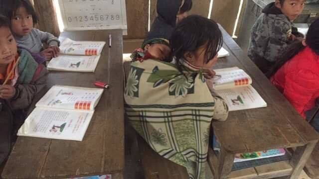 Bé gái đi học phải địu theo em để trông cho bố mẹ đi làm