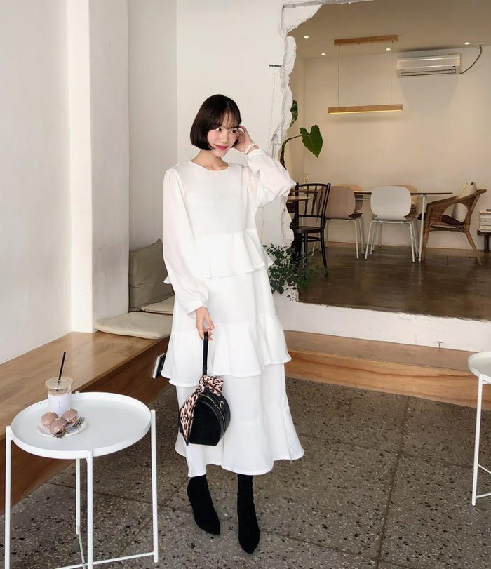 Chiếc đầm trắng xếp tầng form rộng che giấu đi hoàn toàn khuyết điểm ngoại hình, nhờ phối với boots cổ cao, túi xách da báo, set đồ này trở nên cá tính hơn rất nhiều.