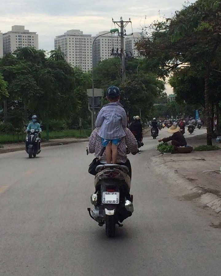 Mẹ không đội mũ bảo hiểm cho con mà còn cho đứng hẳn lên yên xe.