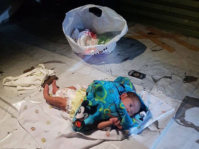 Em bé khoảng 2 tuần tuổi bị bỏ lại trước quầy hàng bán nước dừa.