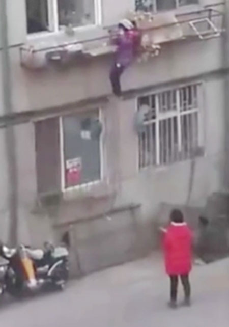 Bé gái đu bám nguy hiểm trên lan can.