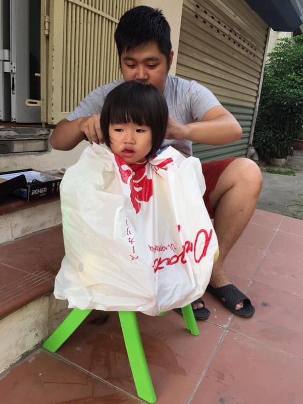 Cô bé được bố trùm túi nilon và cắt tóc cho rất chuyên nghiệp.