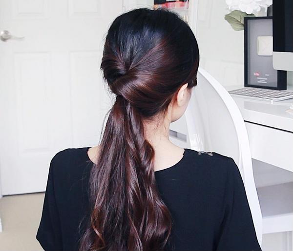 Buộc tóc đuôi ngựa thấp sau đó tẽ đôi phần tóc phía trên nút buộc, cuộn đuôi tóc qua kẽ hở đó.