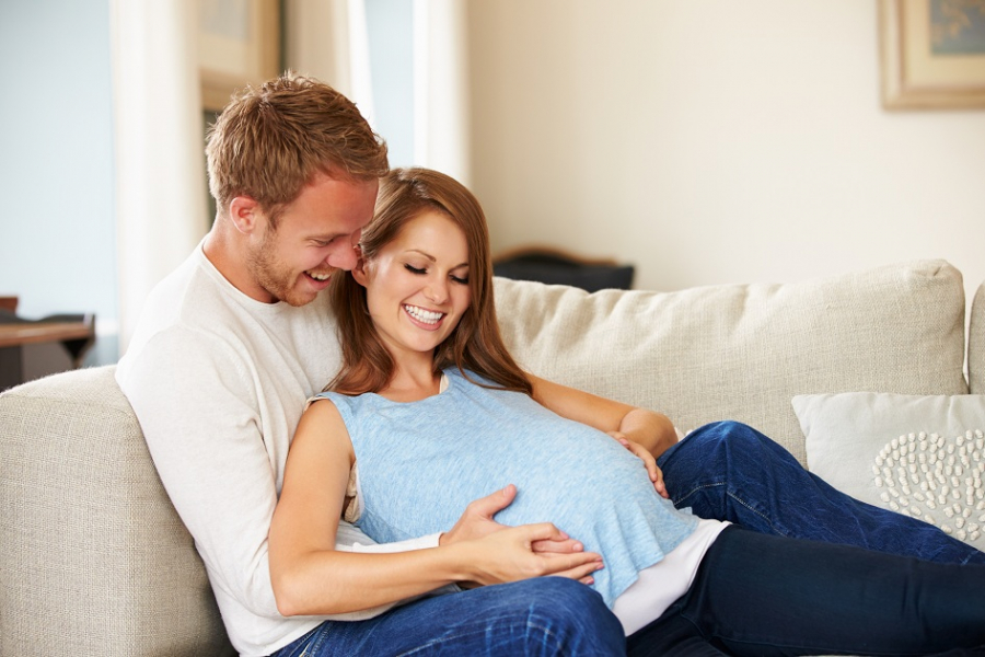 casal-feliz-deitado-sofa-mulher-gravida